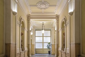 Eine prachtvolle Halle mit klassischer Architektur, mit Säulen, einem großen Bogenfenster und einer hängenden Leuchte.