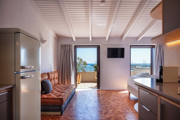 Ein modernes Hotelzimmer mit Sofa, Küchenzeile und Balkon mit Meerblick.
