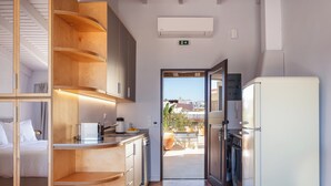 A compact hotel room with a kitchenette, a bed, and a view of the outside. - Chryssi 03, seafront cozy suite for 2 in Rethymno! (Rethymno)