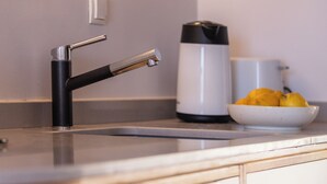 A modern kitchen with a stainless steel sink, a black faucet, a white coffee maker, and a bowl of lemons on the counter. - Chryssi 03, seafront cozy suite for 2 in Rethymno! (Rethymno)