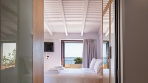 A bedroom with a bed, a TV, and a view of the sea. - Chryssi 03, seafront cozy suite for 2 in Rethymno! (Rethymno)