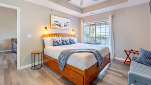A bedroom with a wooden bed, a ceiling fan, a window with curtains, and a small table. - Highland Shores Haven Fit For 7 (Lake Ozark)