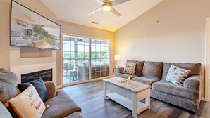 A living room with a fireplace, two sofas, a coffee table, and a ceiling fan. - Highland Shores Haven Fit For 7 (Lake Ozark)