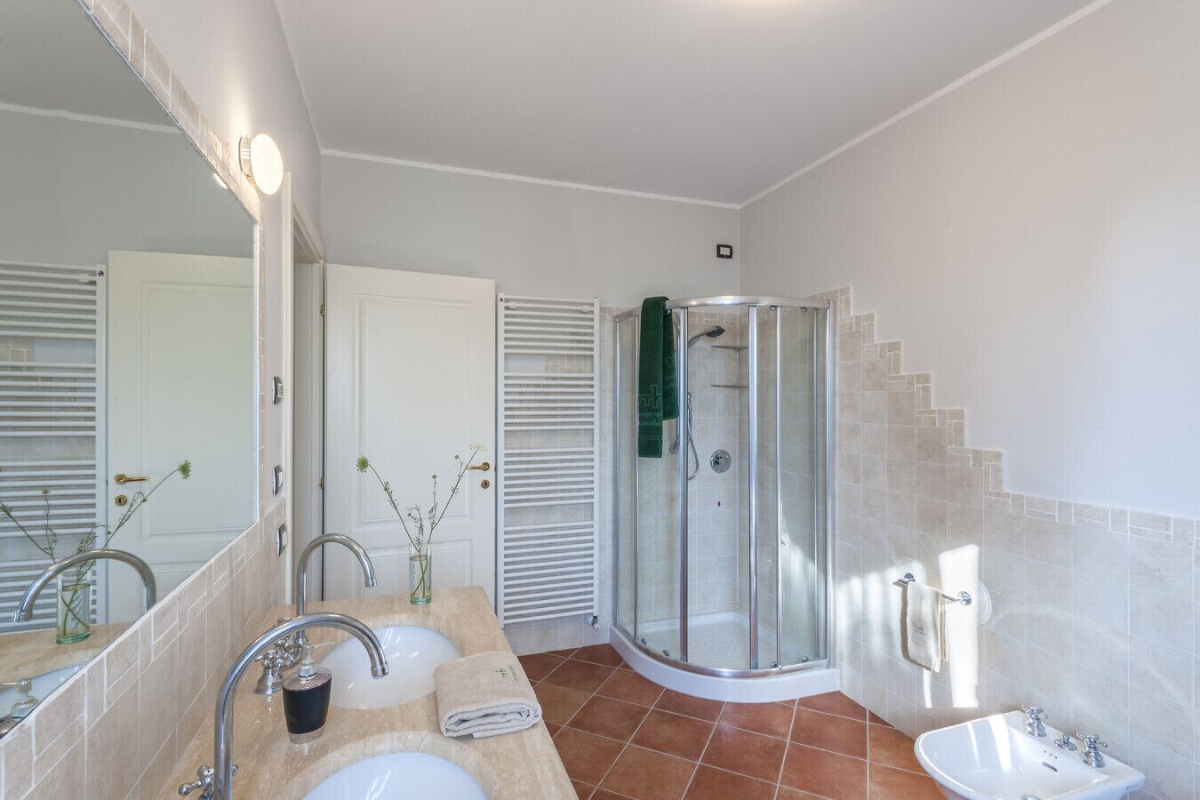 Une salle de bain avec une douche à parois de verre, un lavabo avec un miroir et un porte-serviettes.