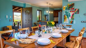 A dining area with a long wooden table set for a meal, chairs, and a view of the outdoors. - Villa Traiani 8&2 by Marche Holiday Villas (Piagge)