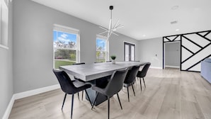 Un comedor moderno con una mesa grande, sillas negras y una lámpara de techo original.
