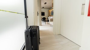 Un couloir avec une valise, une porte et un panneau indiquant « POUSSER ».