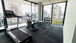 Une salle de sport équipée d’un tapis de course, d’un vélo elliptique, d’un banc de musculation et d’haltères.