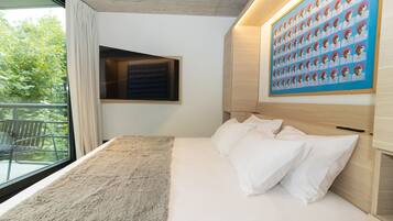 Una habitación de hotel moderna con una cama grande, vistas a zonas verdes y una obra de arte en la pared.