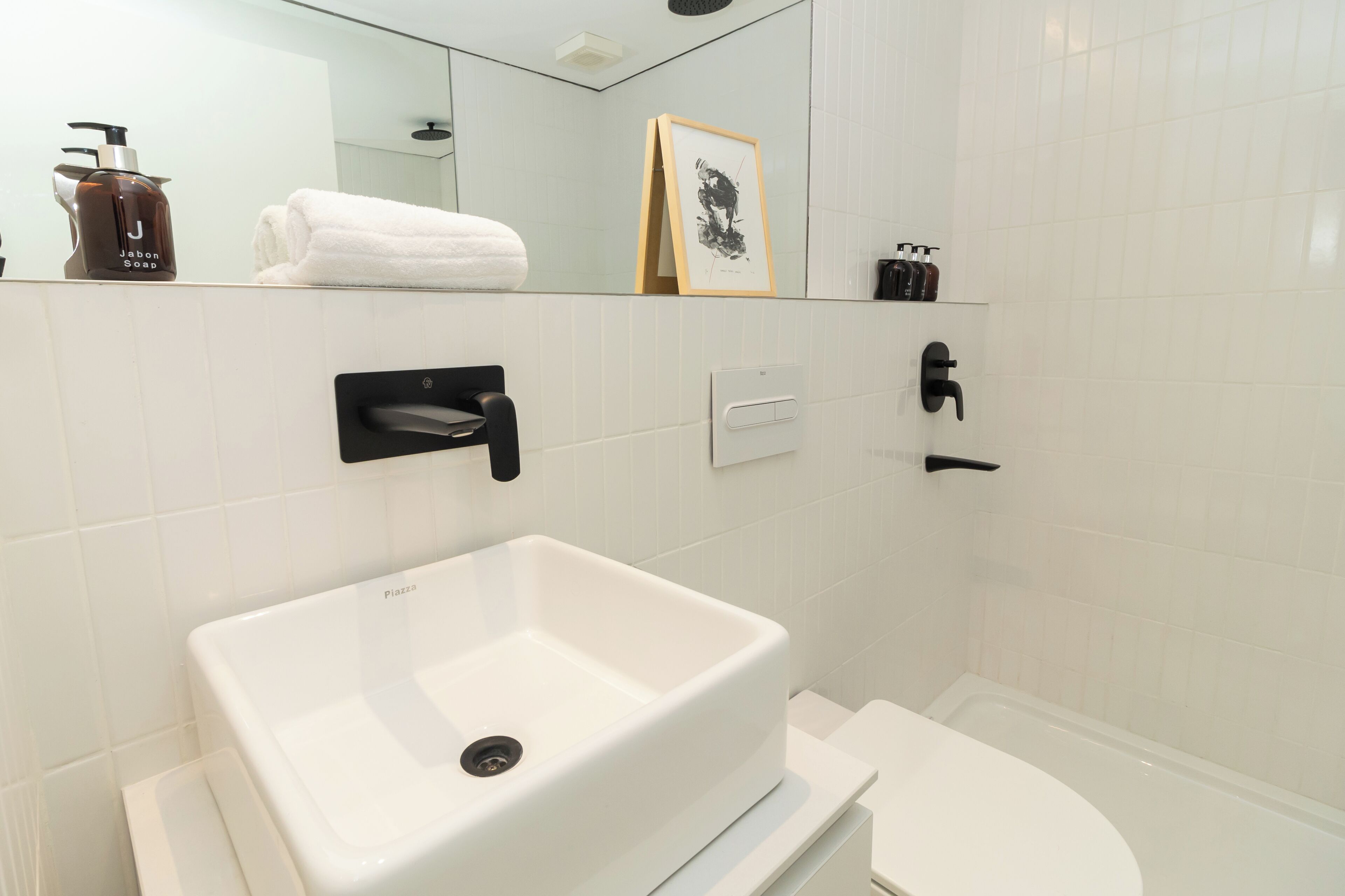 Un baño moderno con lavamanos blanco, inodoro y zona de ducha.