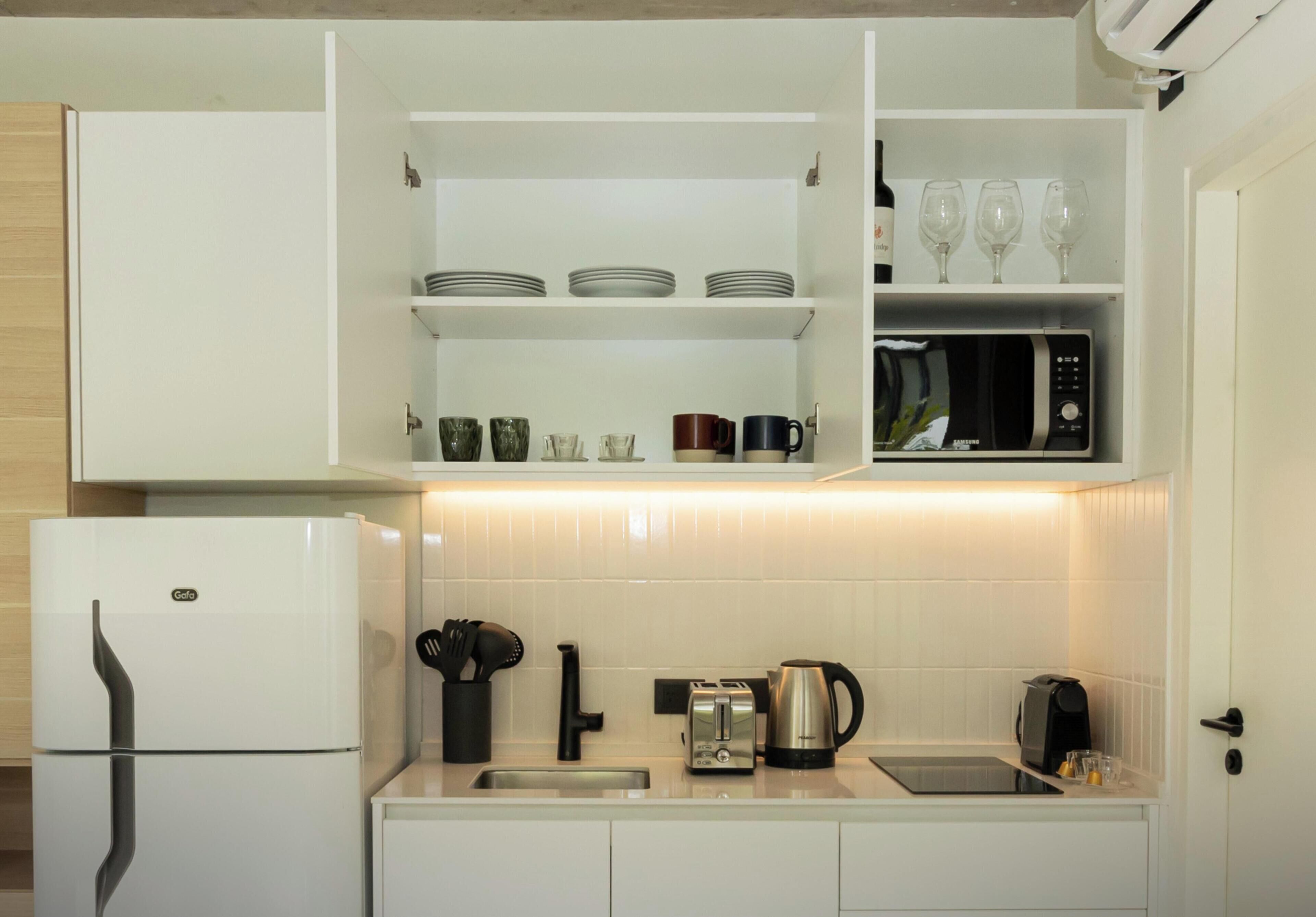 A modern kitchen with white cabinets, a built-in microwave, a toaster, and a coffee maker.