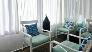 A room with four white chairs with teal cushions, a small table, and a black lantern.