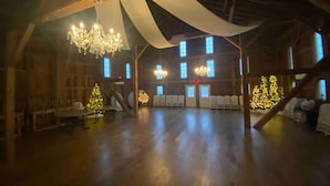 A spacious hall with wooden floors, white drapes, and chandeliers. - Rock Run Creek House (Goshen)