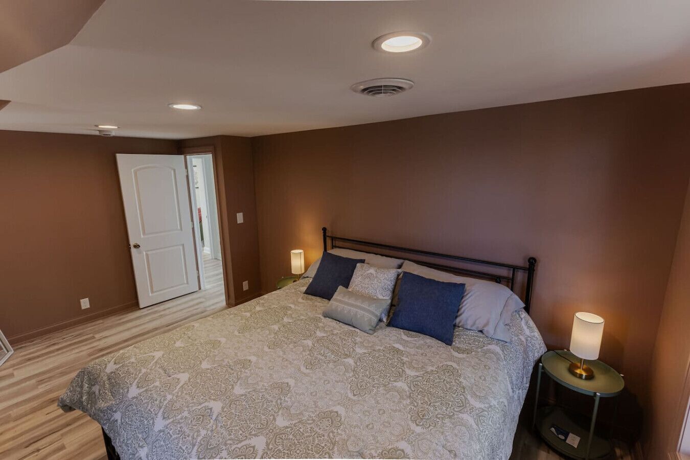 Una camera da letto con un letto, due abat-jour, una porta e una luce a soffitto.
