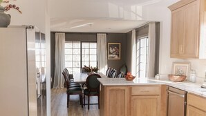 Eine moderne Küche mit Holzausstattung, einer Marmorarbeitsplatte und einem Essbereich mit Tisch und Stühlen.
