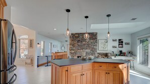 Una cocina amplia con una isla grande, armarios de madera e iluminación colgante.