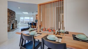 Un comedor con una mesa de madera dispuesta para cuatro personas, una chimenea de piedra y vistas al exterior.