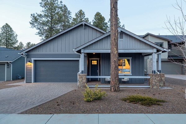 A two-story house with a grey exterior, a front porch, and a garage.
