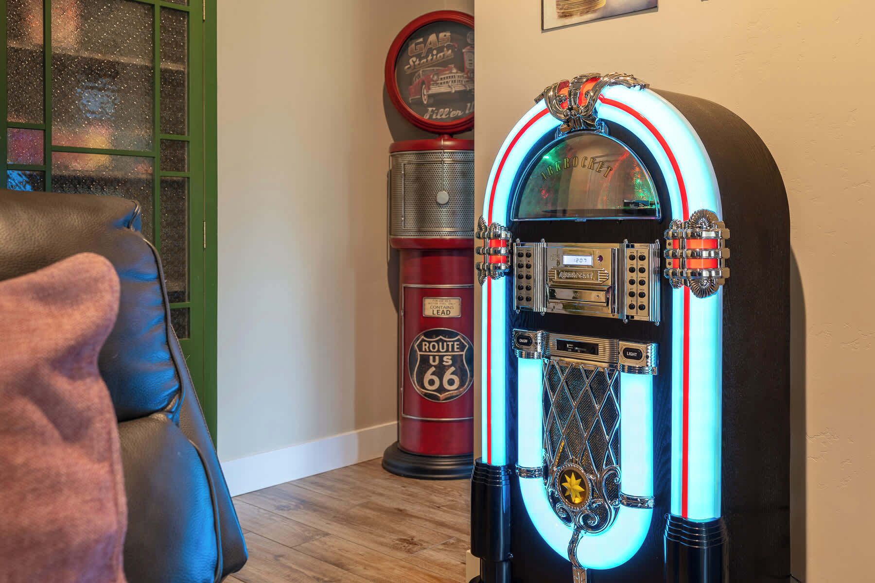 Eine Jukebox mit Neonlichtern und ein altes Tankstellen-Schild im Hintergrund.