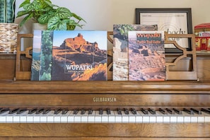 A piano with books titled 'Wupatki National Monument' and 'Vupatki Pueblo Trail Guide' on top.