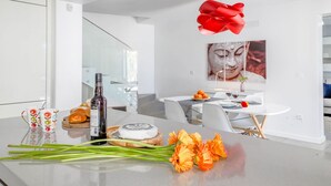 Eine moderne Küche mit Essbereich, ausgestattet mit einer Glaskonstruktion als Treppe, einem roten dekorativen Element und einer Buddha-Statue an der Wand.