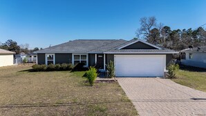 A single-story house with a garage, a front yard, and a satellite dish on the roof. - Charming Cozy  3-bedroom house with WiFi, fitness room in lovely Ocala (Ocala)