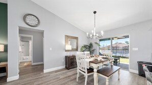 A dining area with a wooden table and chairs, a chandelier, and a view through glass doors. - Charming Cozy  3-bedroom house with WiFi, fitness room in lovely Ocala (Ocala)