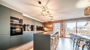 A modern kitchen with built-in appliances, a central island, and bar stools.