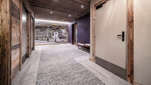 A hallway with wooden walls and a tiled floor leading to a room with a door.