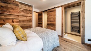 A bedroom with a bed, wooden walls, a sliding door, and a towel rack.
