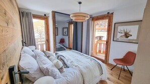 Et soveværelse med en stor seng, trævægge, en rød stol og et billede af et rådyr på væggen.