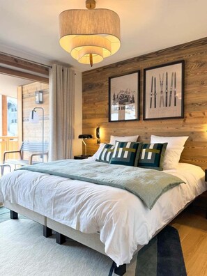Une chambre à coucher moderne avec un grand lit, des lambris en bois sur les murs et deux tableaux encadrés.