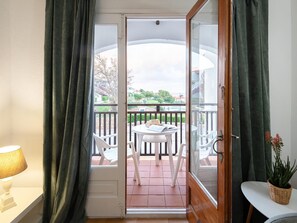 Enjoy a room with a balcony offering a view, featuring a table and chairs, and a potted plant.