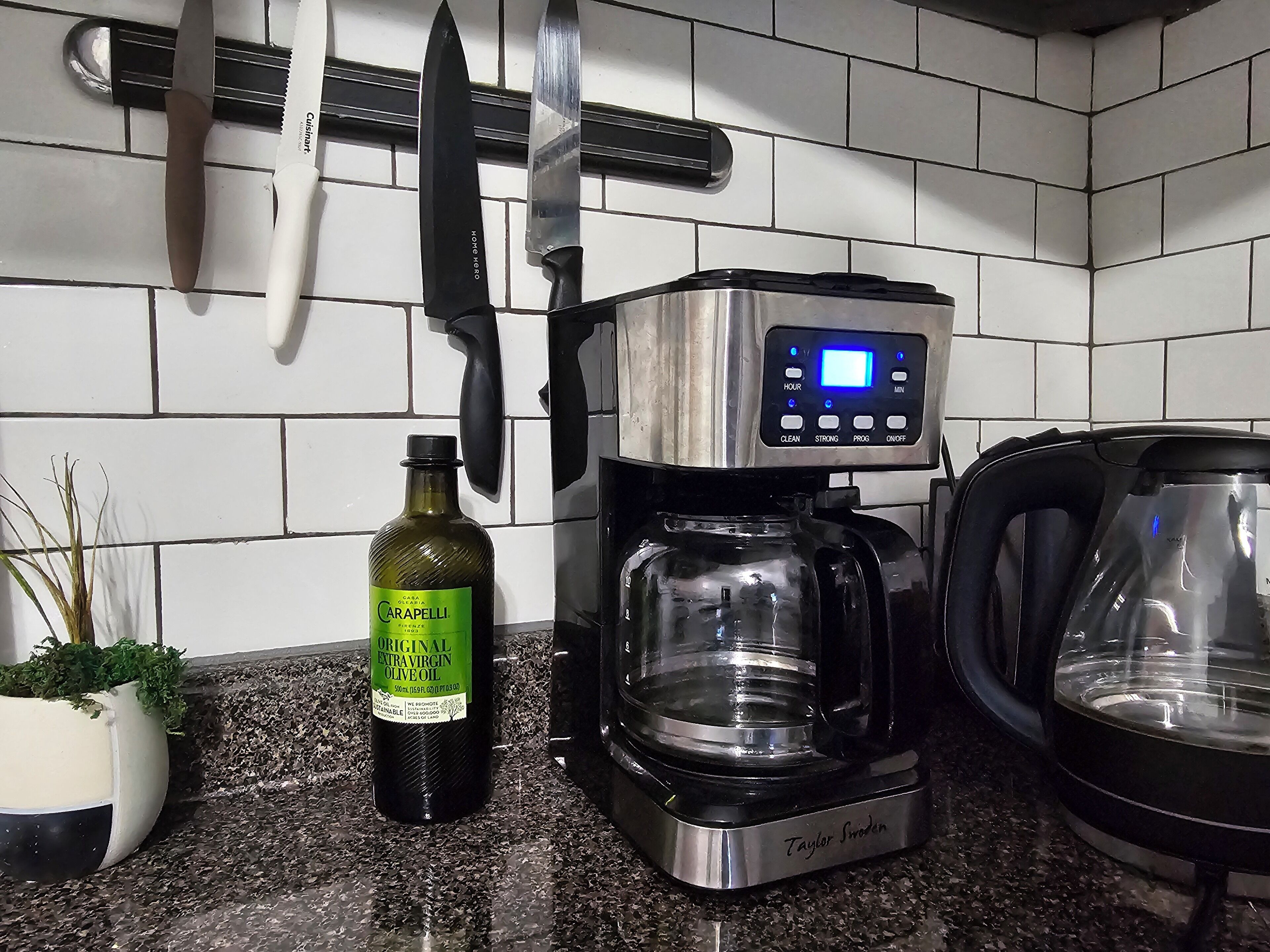 A kitchen with a coffee maker, a kettle, and a bottle of olive oil on the counter.