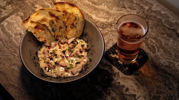A bowl of food with bread and a glass of beer on a textured surface.