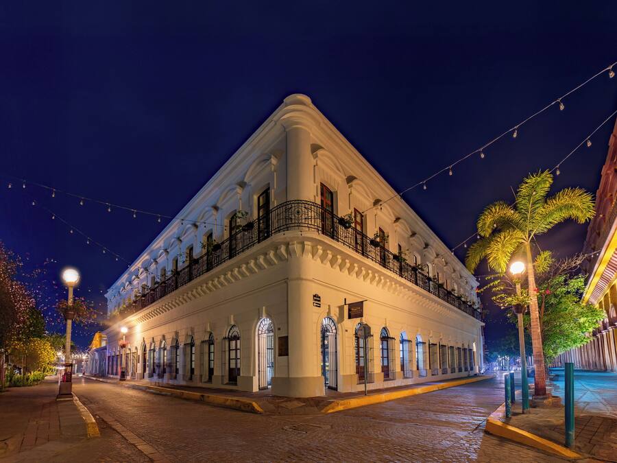 A historic building with a white facade, multiple balconies, and a corner location.