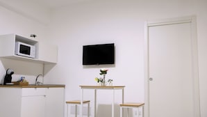 A small kitchenette with a microwave, a sink, and a television mounted on the wall.