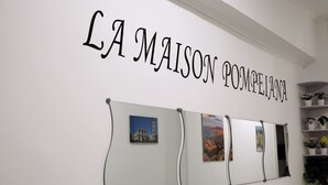 A wall with the text "LA MAISON POMPELIANA" and three framed pictures.