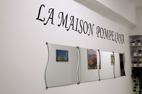Eine Wand mit dem Schriftzug "LA MAISON POMPELIANA" und drei gerahmten Bildern.