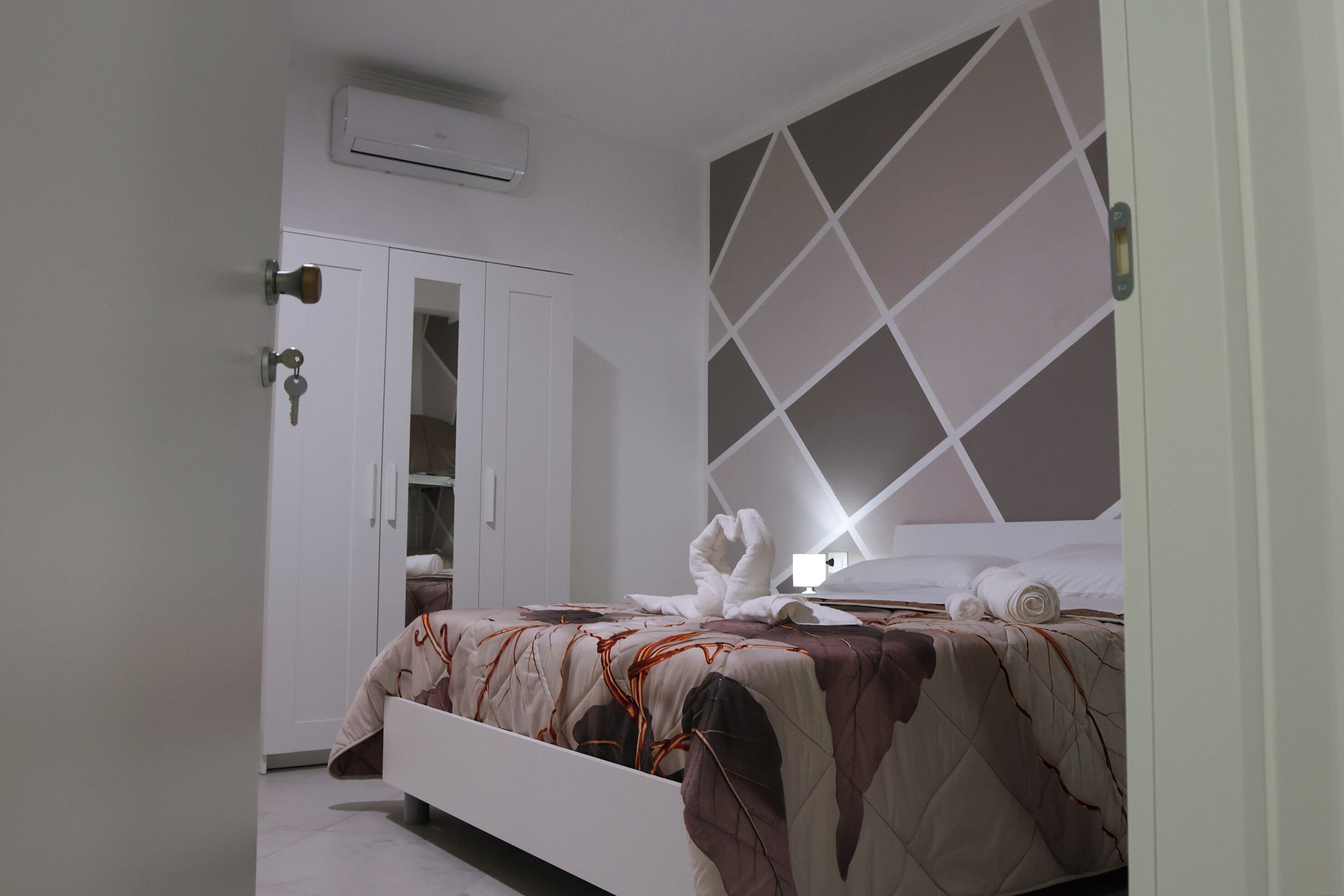 Un dormitorio con cama, armario y aire acondicionado instalado en la pared.