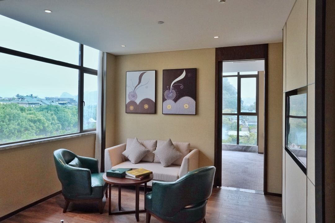 Una habitación moderna con un sofá, dos sillones, una mesita y una obra de arte en la pared.