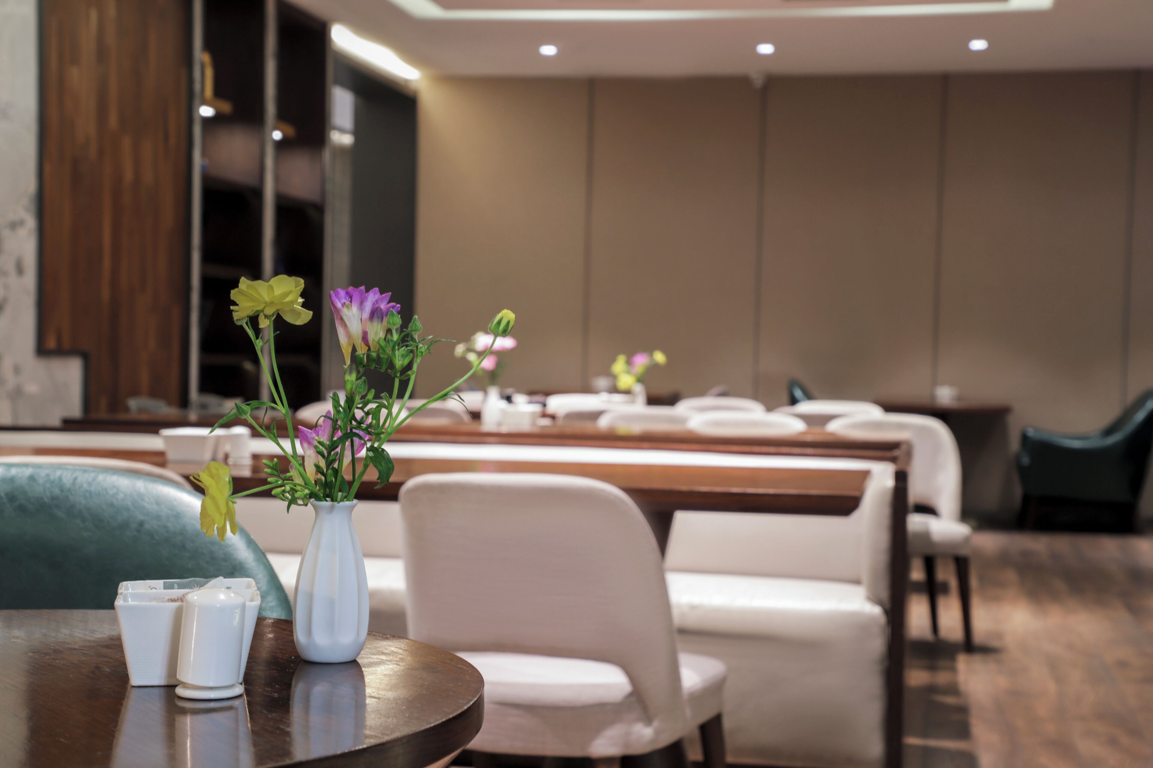 Un espace repas moderne avec une table ronde, des chaises blanches et un vase rempli de fleurs.
