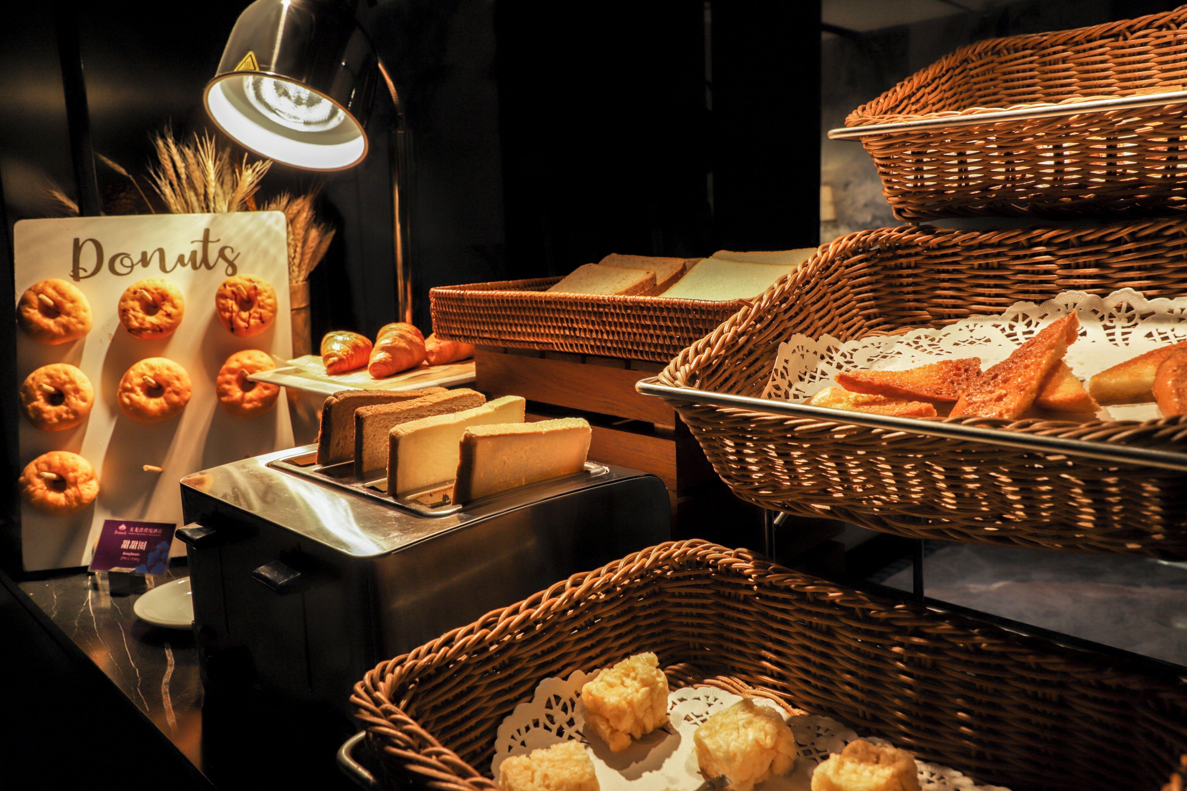 Un bufé con diversas opciones de panadería, incluyendo rosquillas, pan y pasteles.