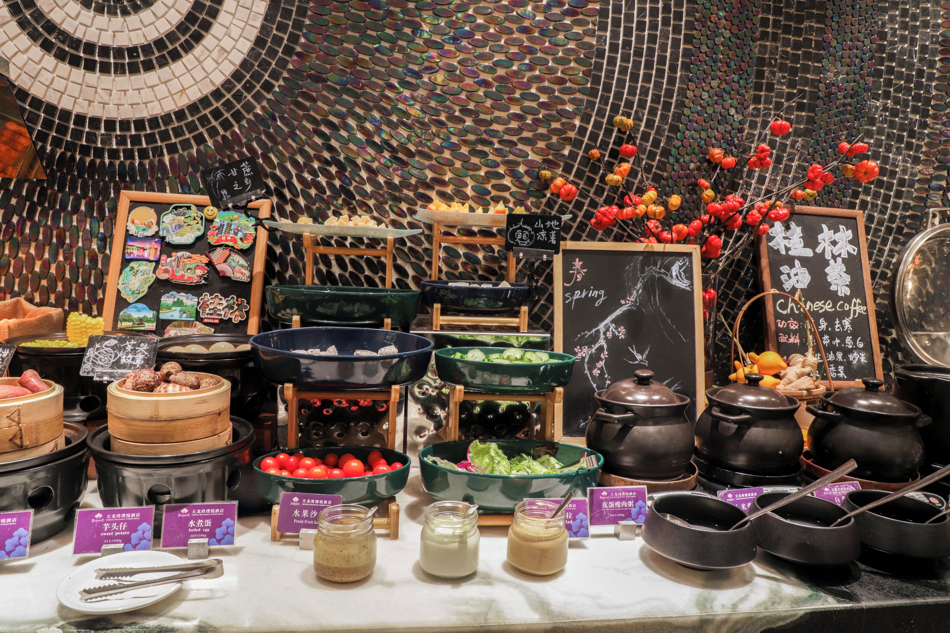 A variety of food items and condiments displayed on a counter with a decorative tiled wall in the background.