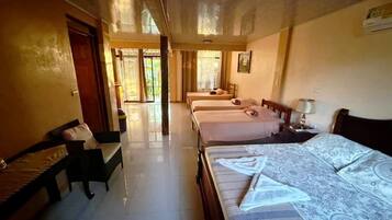 Una habitación de hotel con dos camas, un banco, un escritorio y un ventanal grande.
