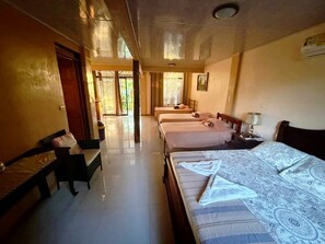Une chambre d’hôtel avec deux lits, un banc, un bureau et une grande fenêtre.