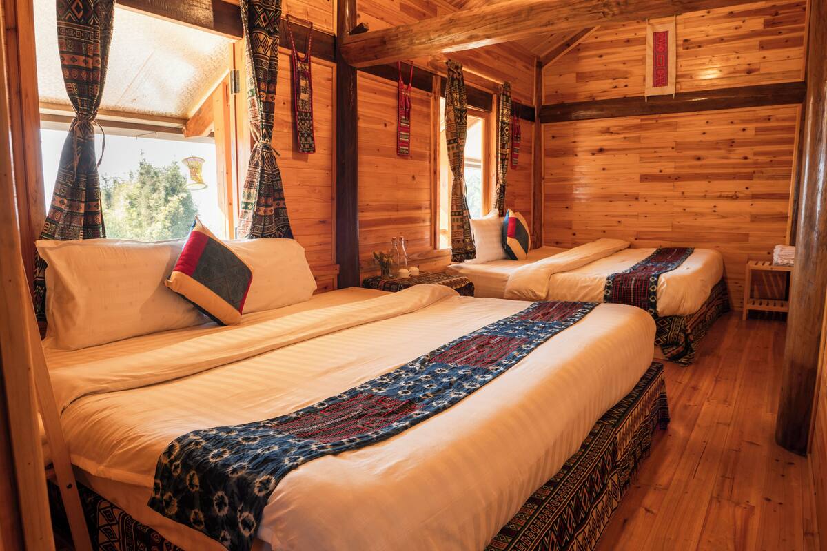 A wooden cabin with two beds, each with a patterned bedspread and pillows.