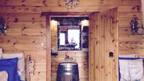 A wooden cabin room with a bed, a wooden barrel, a clock, and a mirror. - Ambelli The Pirates Cabin - Black Pearl (Kalymnos)