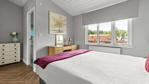Une chambre à coucher avec un lit, une commode et une fenêtre donnant sur des immeubles.