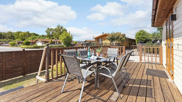 Une terrasse en bois avec des meubles d’extérieur, une vue sur les environs et un bâtiment à l’extérieur en bois.